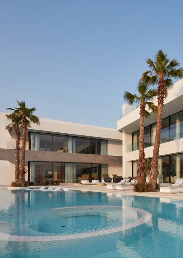 A picture of a villa featuring a swimming pool and palm trees